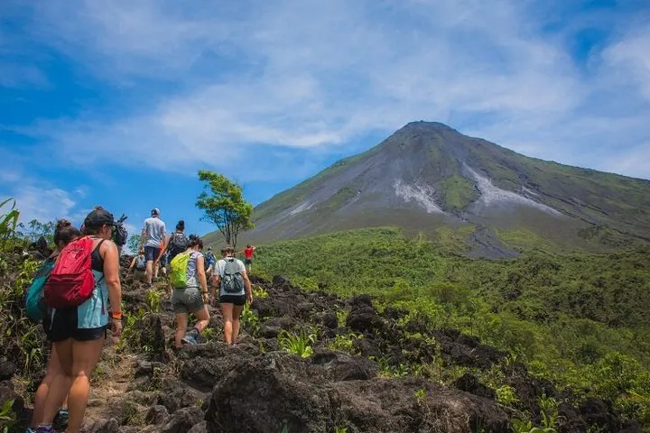 Travelers soaking in a natural hot springs river after a morning hike on an Arenal volcano hot springs tour in La Fortuna, Costa Rica