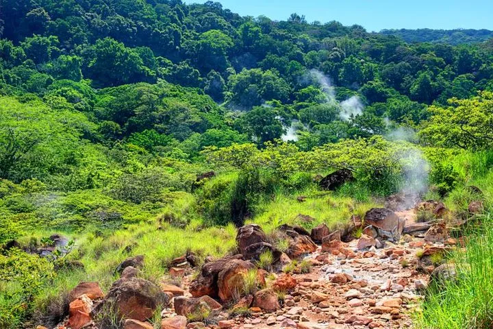 Hikers approaching a waterfall pool before a hot springs soak on a Rincon de la Vieja volcano hot springs tour in Guanacaste, Costa Rica